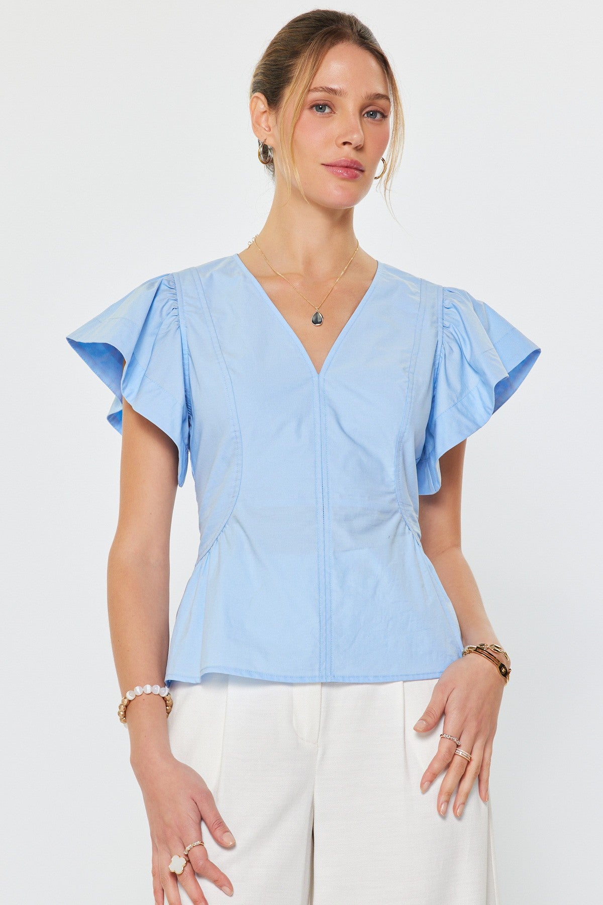 V-neck top with flutter sleeves and tailored waist detail styled with light bottoms