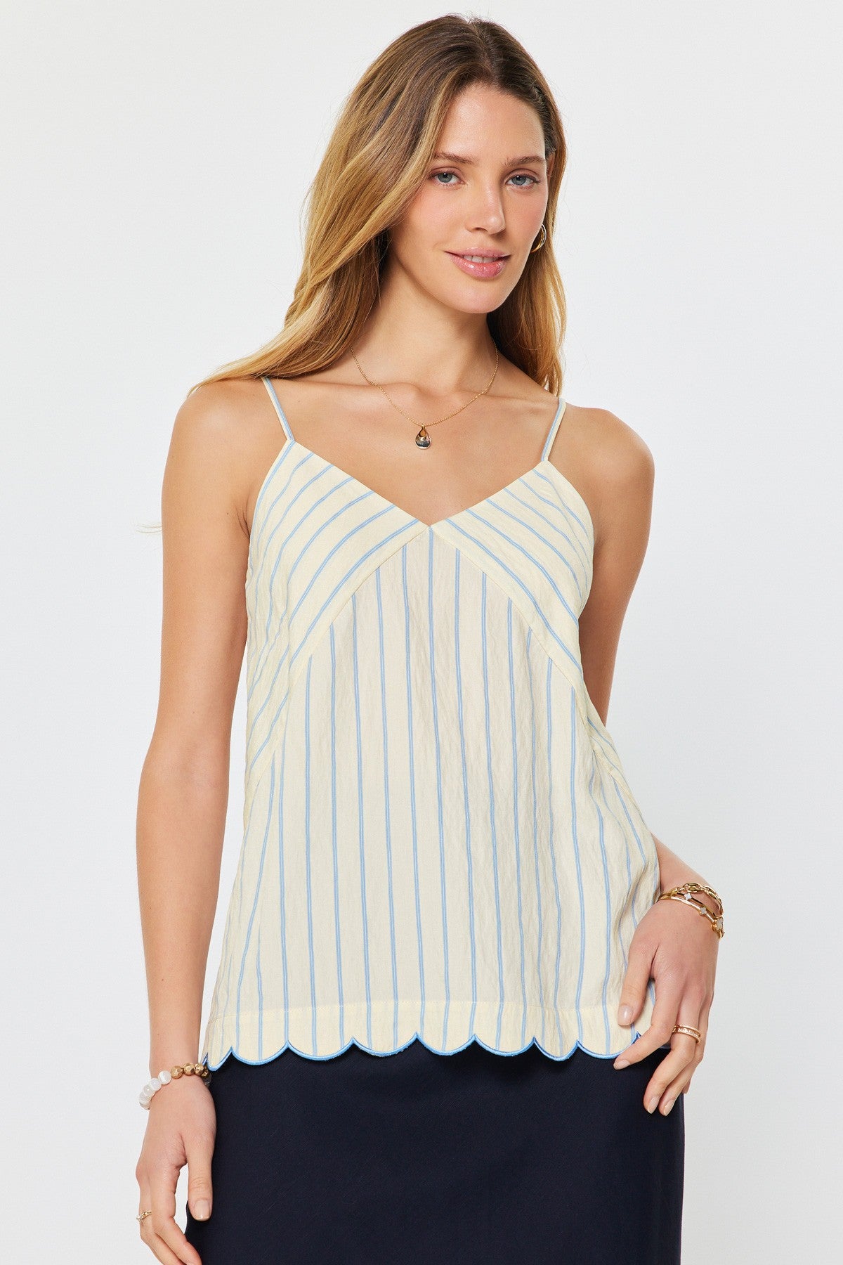woman wearing a striped camisole tank with thin straps and scalloped hem detail styled with a midi skirt