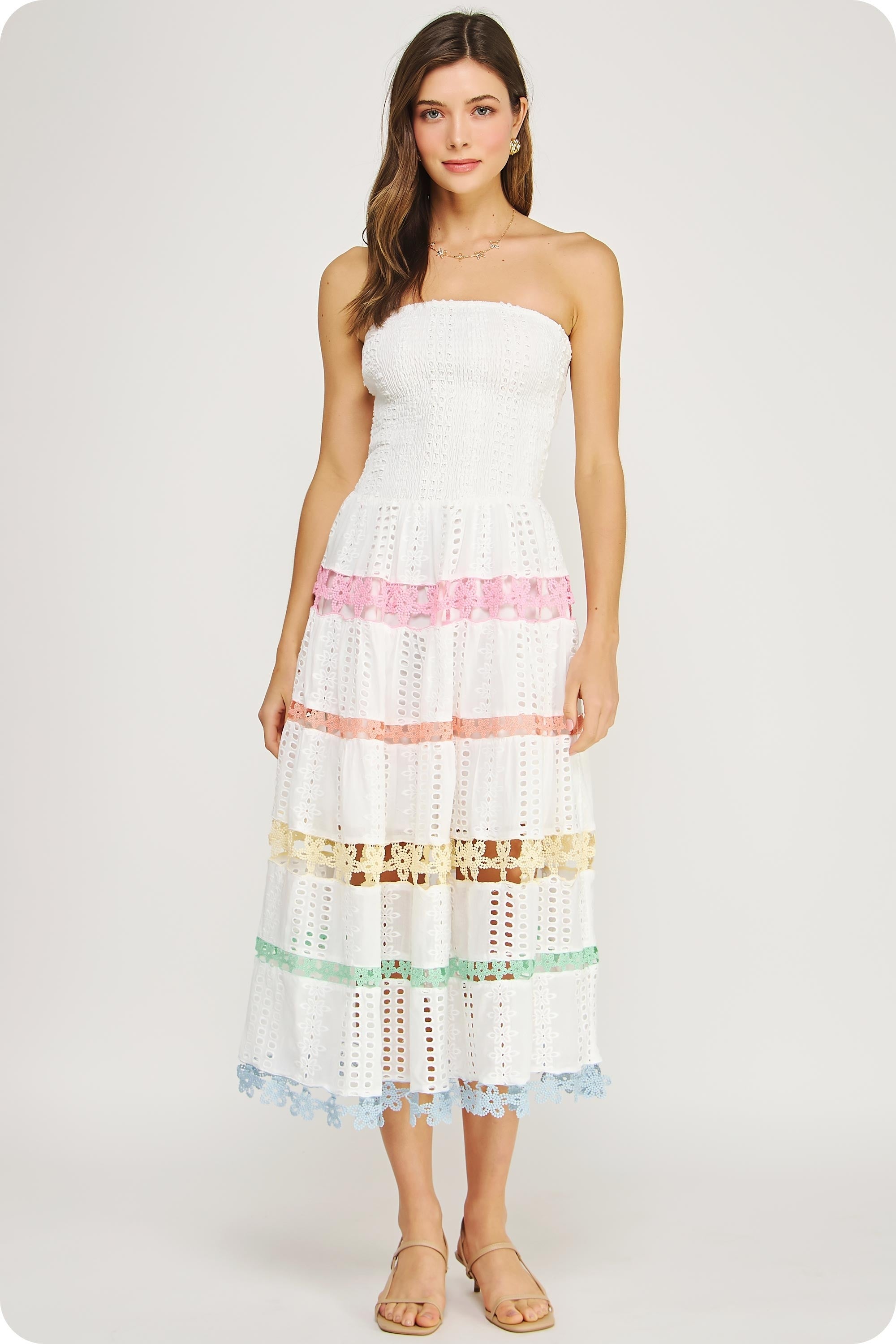 Strapless white eyelet midi dress with a smocked bodice, tiered skirt, and pastel lace trim details throughout.