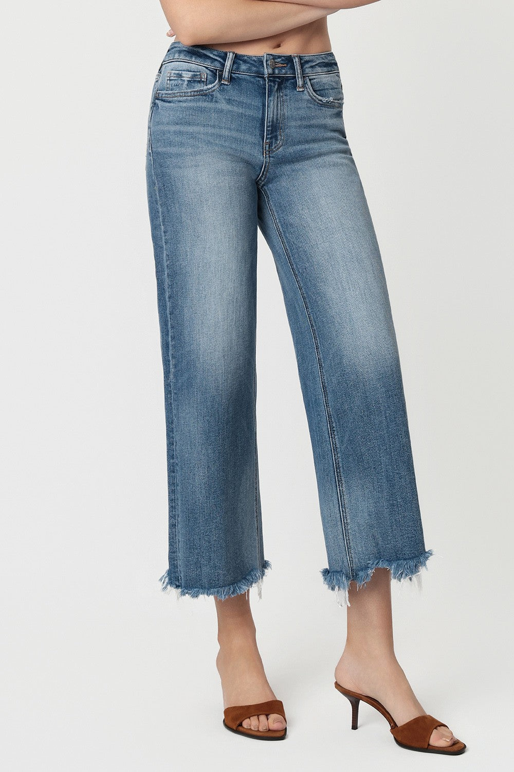 Cropped wide leg jeans with a high-rise fit and frayed hem styled with heeled sandals