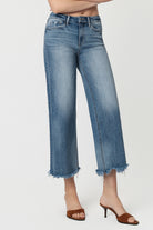 Cropped wide leg jeans with a high-rise fit and frayed hem styled with heeled sandals