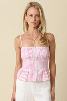 Pink striped camisole top with button-front detail, lace trim, adjustable straps, and smocked back paired with white pants.