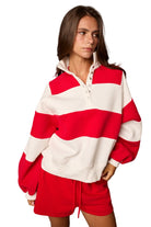 Model wearing a striped half-snap pullover sweatshirt with an oversized fit and matching drawstring shorts.