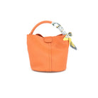 Scarf Tie Handbag Orange. This adorable handbag features a bucket design with a scarf detail on the top handle and a snap closure, the perfect pop of color to add to any outfit.