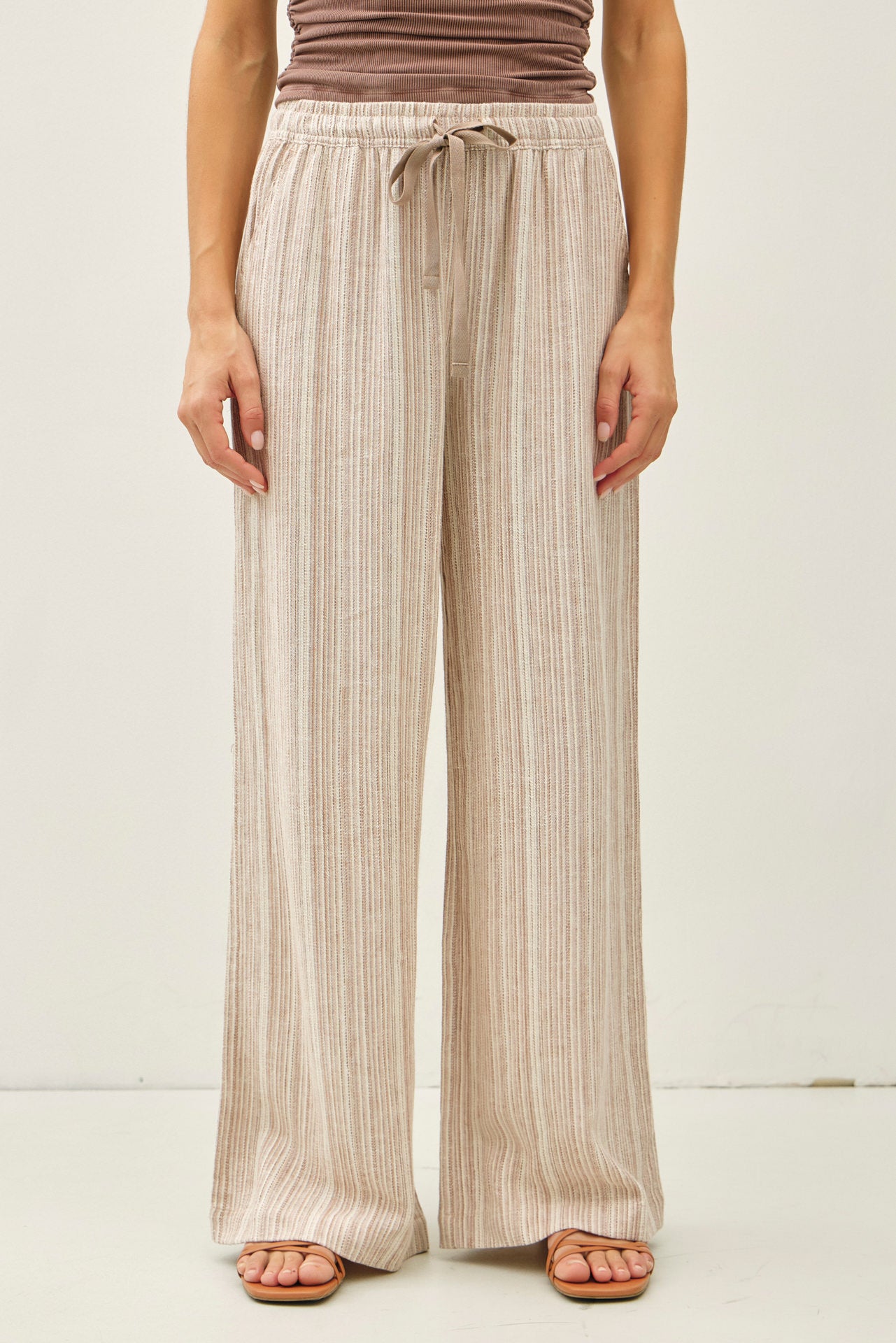 Wide-leg pants with elastic drawstring waistband and subtle textured fabric, styled with sandals.