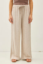 Wide-leg pants with elastic drawstring waistband and subtle textured fabric, styled with sandals.