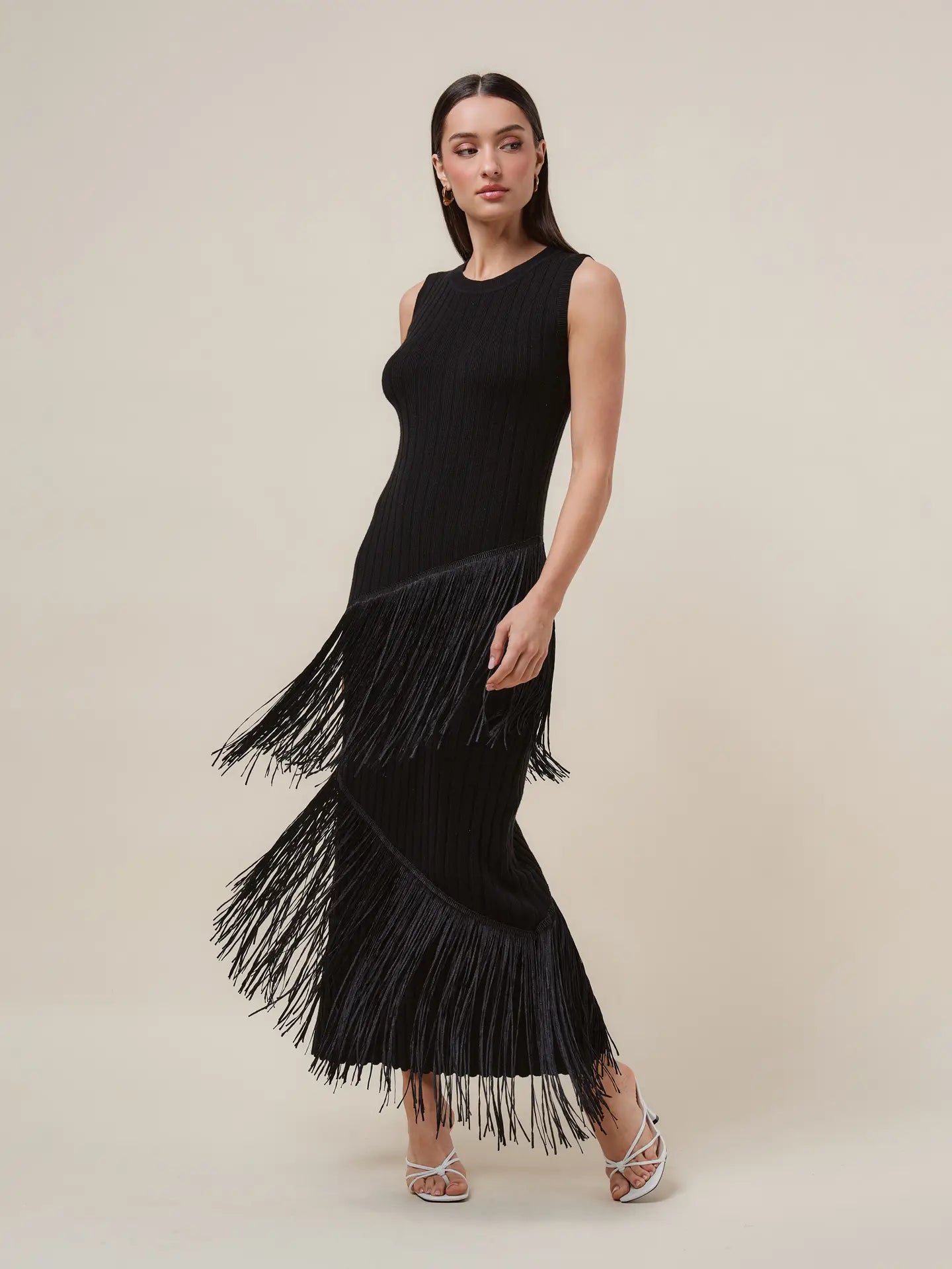 Sleeveless ribbed knit midi dress with a fitted silhouette and cascading fringe detailing throughout the skirt and hem.