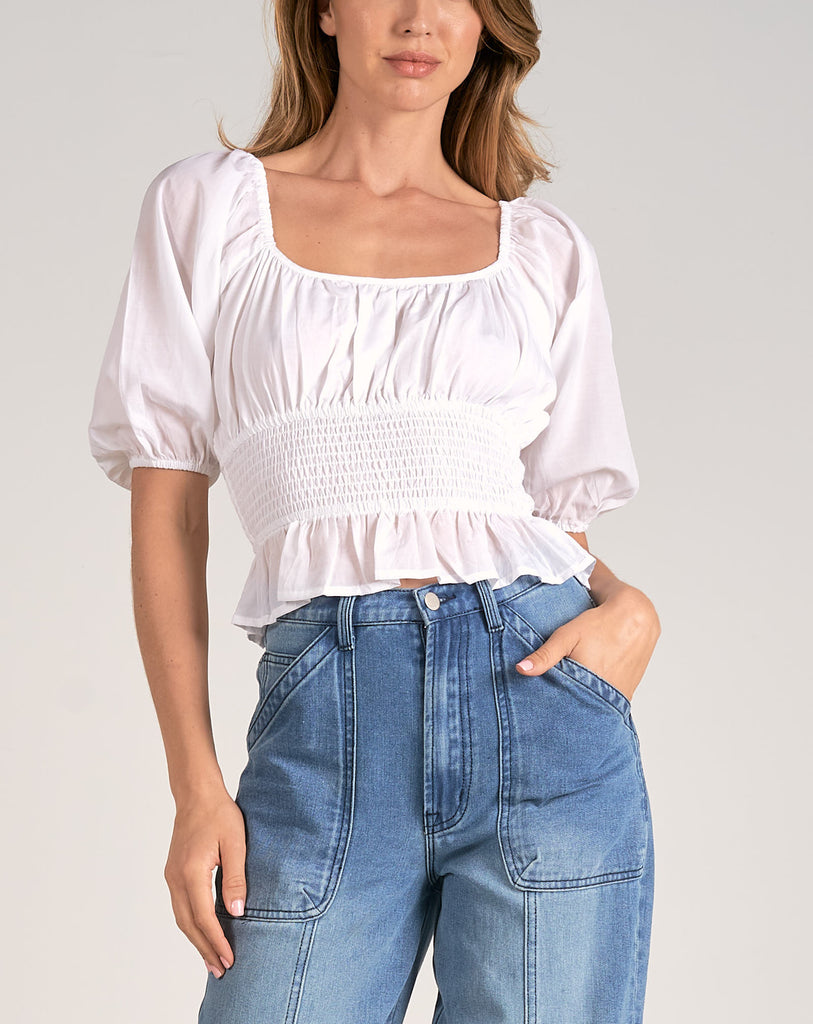 Elan Smock Waist Top White. This peasant style top features a smocked waist with a square neckline, perfect for pairing with distressed jeans for an easy everyday look.
