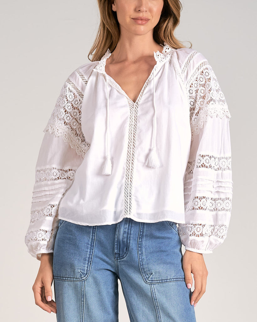 Elan Crochet Blouse White. This blouse features a tie neck with beautiful crochet detail on the sleeves, wear it tucked in or out with your favorite blue jeans for a boho chic everyday look.