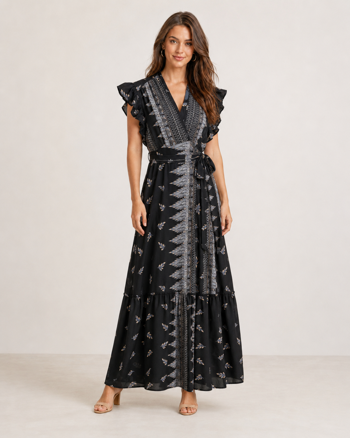 woman wearing a blue printed sleeveless wrap maxi dress with ruffle trim on the sleeves and a tie waist