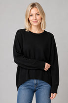 Woman wearing a relaxed crewneck sweater with dropped shoulders, ribbed trim, side slits, and a high-low hem.