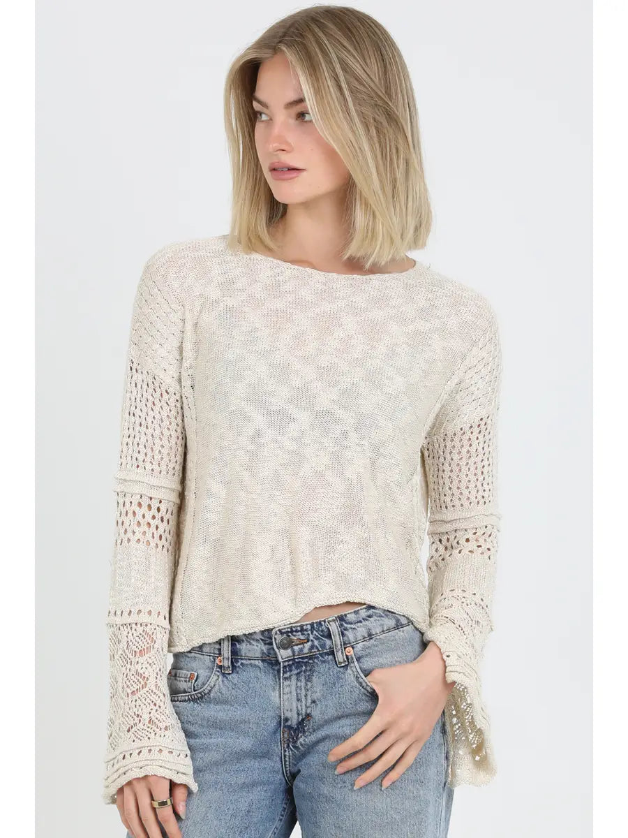 Lightweight open knit sweater with long sleeves and relaxed fit styled with denim jeans