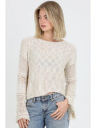 Lightweight open knit sweater with long sleeves and relaxed fit styled with denim jeans