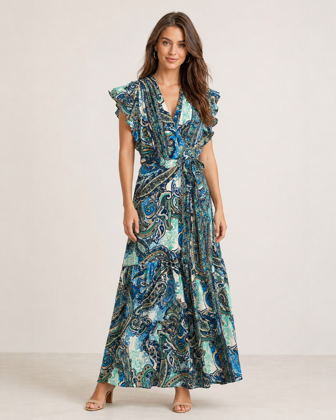 woman wearing a blue printed sleeveless wrap maxi dress with ruffle trim on the sleeves and a tie waist