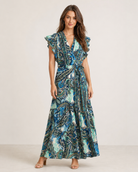 woman wearing a blue printed sleeveless wrap maxi dress with ruffle trim on the sleeves and a tie waist