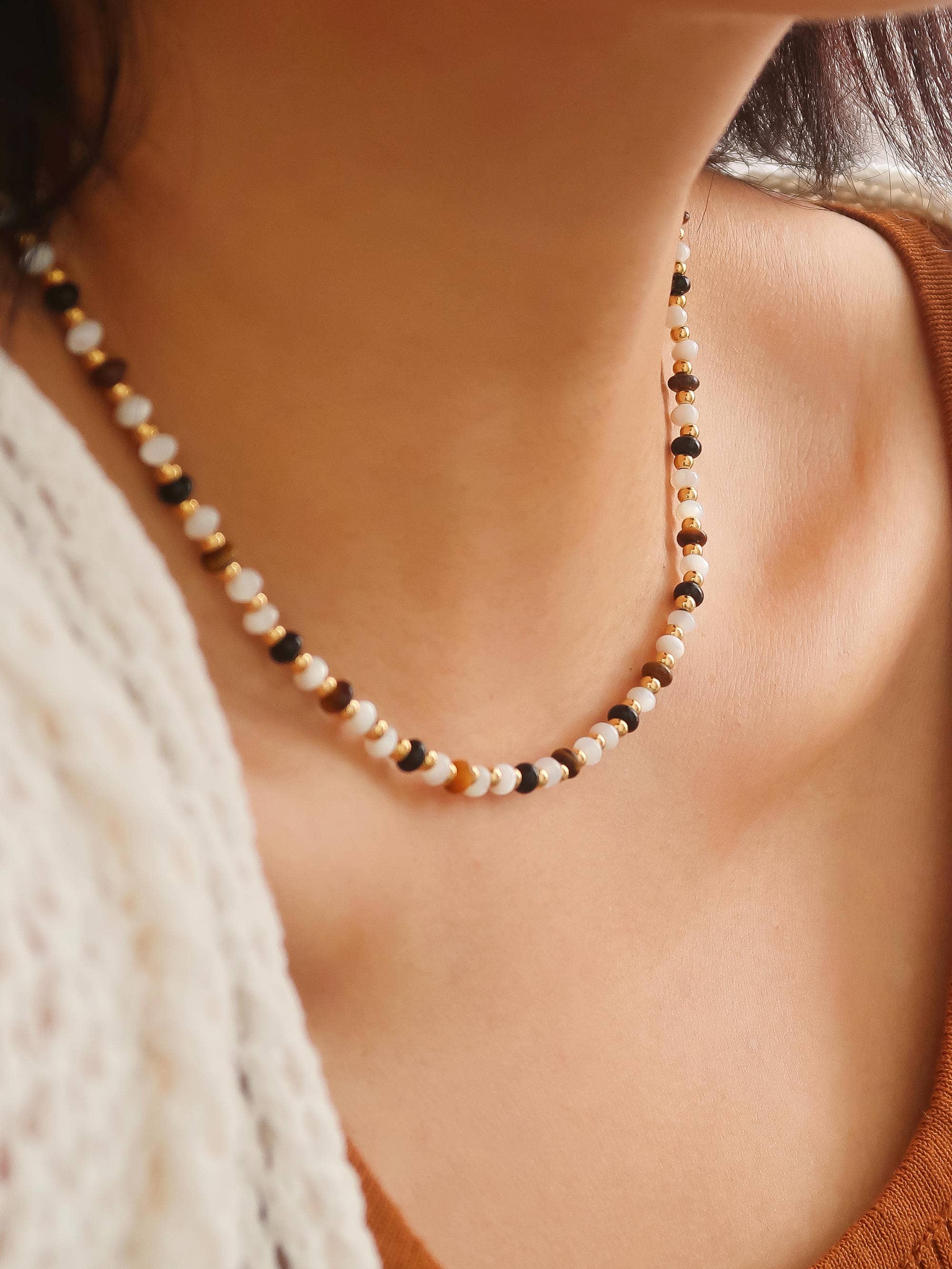Beaded choker necklace featuring alternating black, ivory, and gold-tone beads on a delicate strand, styled as a modern everyday accessory.