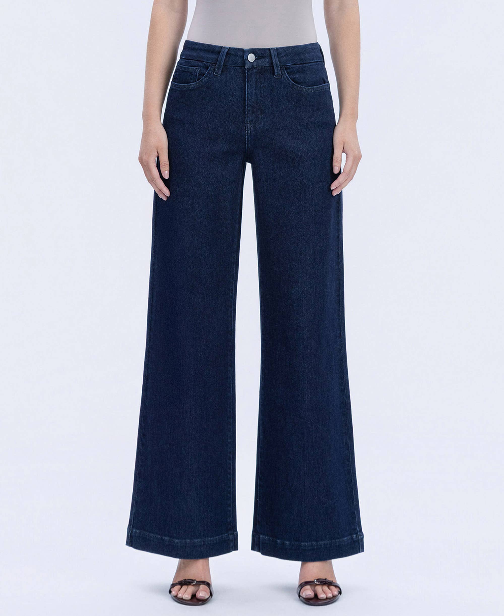 Model wearing high-rise dark wash wide-leg jeans with a clean finish, styled with a fitted neutral bodysuit and sandals against a white studio background.