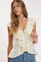Women's sleeveless ruffle blouse with lace trim, button-front closure, peplum hem, and a soft, feminine silhouette.