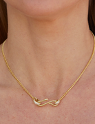 Gold chain necklace with sculptural clasp detail and pavé accents worn on a model.
