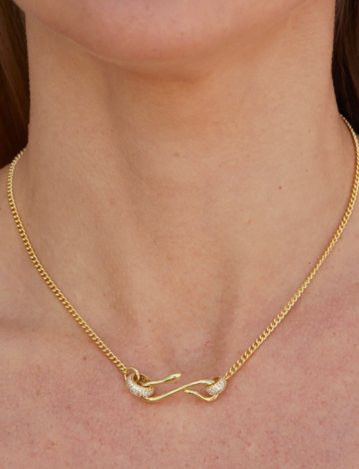 Gold chain necklace with sculptural clasp detail and pavé accents worn on a model.
