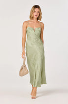 Woman wearing a satin slip midi dress with a fitted silhouette, delicate straps, and subtle floral texture