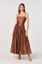 Woman wearing a shimmer midi dress with a fitted bodice, thin straps, and a full gathered skirt