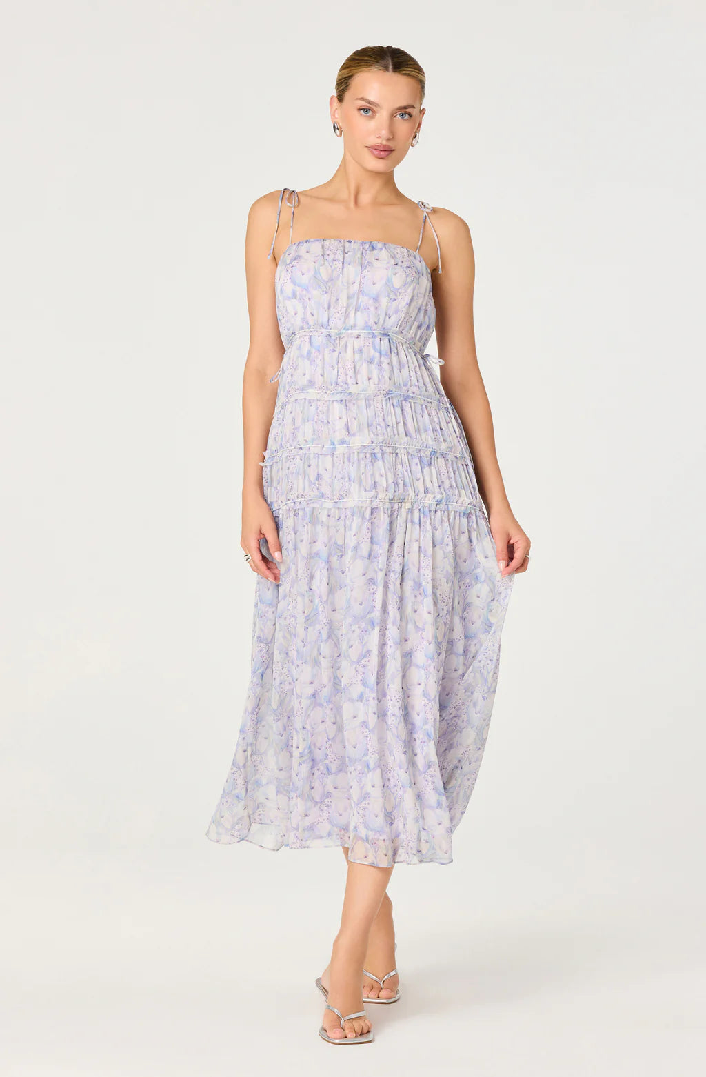 Woman wearing a tiered floral midi dress with delicate straps, a gathered bodice, and a flowy skirt