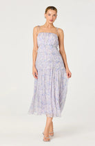 Woman wearing a tiered floral midi dress with delicate straps, a gathered bodice, and a flowy skirt