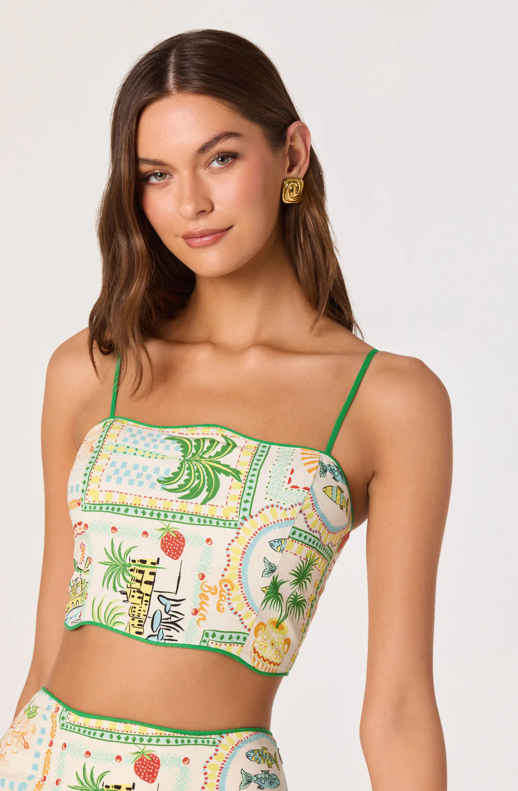 Model wearing a tropical print cropped cami with adjustable spaghetti straps.