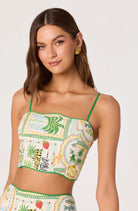 Model wearing a tropical print cropped cami with adjustable spaghetti straps.