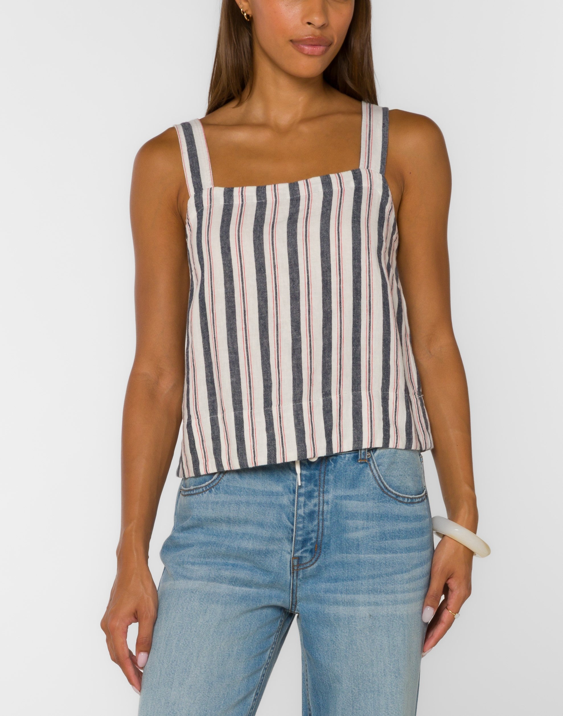 Striped sleeveless tank top with square neckline and relaxed fit paired with light wash denim jeans.