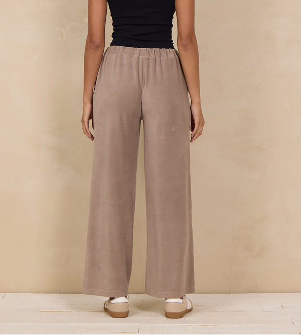 Woman wearing a wide-leg pant with an elastic waist and side pockets.