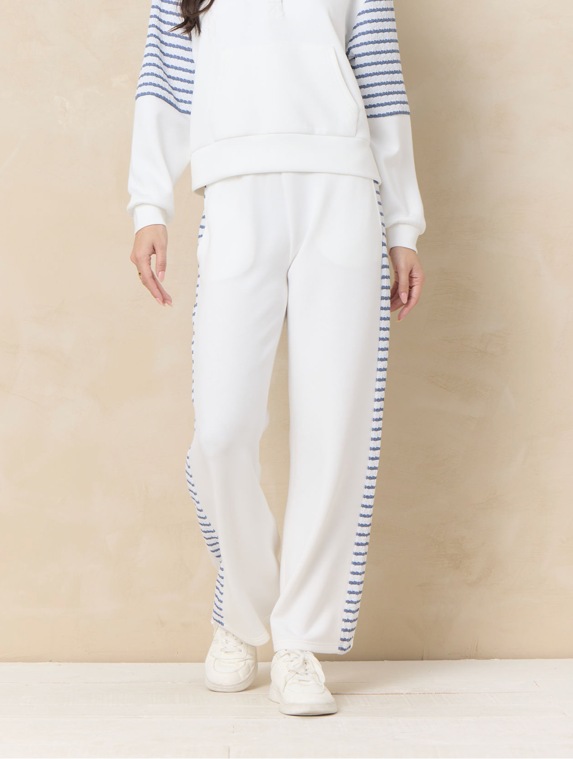 Ivory wide leg lounge pants with striped side panel detailing paired with coordinating relaxed sweatshirt and sneakers.