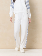 Ivory wide leg lounge pants with striped side panel detailing paired with coordinating relaxed sweatshirt and sneakers.