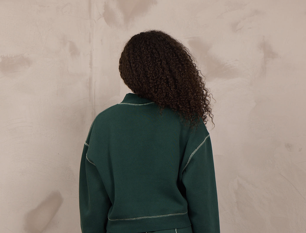 Woman wearing a mockneck pullover with contrast stitching.