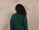 Woman wearing a mockneck pullover with contrast stitching.