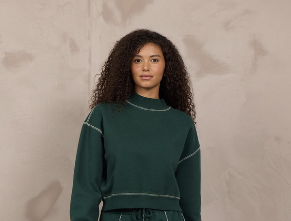 Woman wearing a mockneck pullover with contrast stitching.
