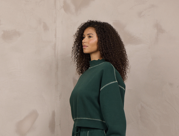Woman wearing a mockneck pullover with contrast stitching.