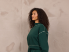 Woman wearing a mockneck pullover with contrast stitching.