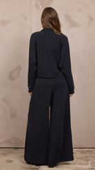 Woman wearing a cropped pinstripe zip-up jacket with a stand collar and ribbed cuffs.