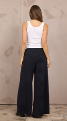 Woman wearing wide-leg pleated-front pinstripe trousers with an elastic waistband.