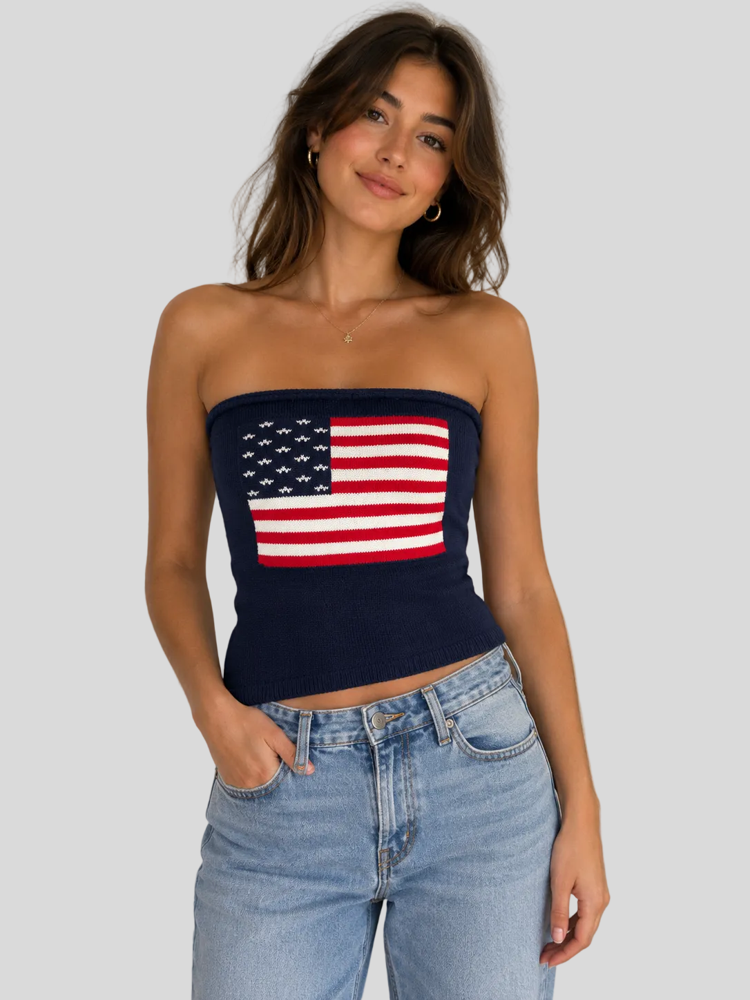 Navy knit strapless sweater tube top with American flag graphic paired with light wash denim jeans.