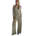 A woman wearing a light heather gray long-sleeve lounge set with matching wide-leg pants, standing in a kitchen environment.