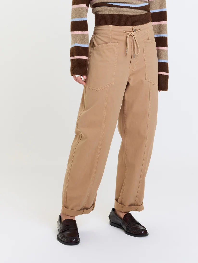 Model wearing relaxed utility pants with oversized patch pockets, an adjustable drawstring waistband, rolled cuffs, and a straight-leg fit.