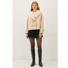 Women's neutral double-breasted cropped peacoat with wide notched lapels, button-tab cuffs, and a relaxed boxy fit