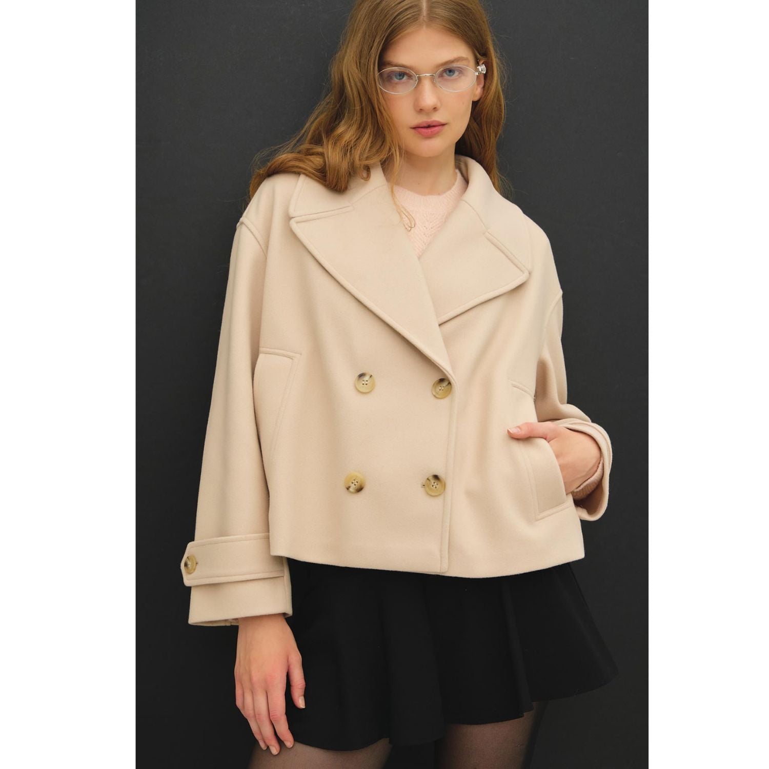 Women's neutral double-breasted cropped peacoat with wide notched lapels, button-tab cuffs, and a relaxed boxy fit
