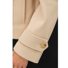 Women's neutral double-breasted cropped peacoat with wide notched lapels, button-tab cuffs, and a relaxed boxy fit