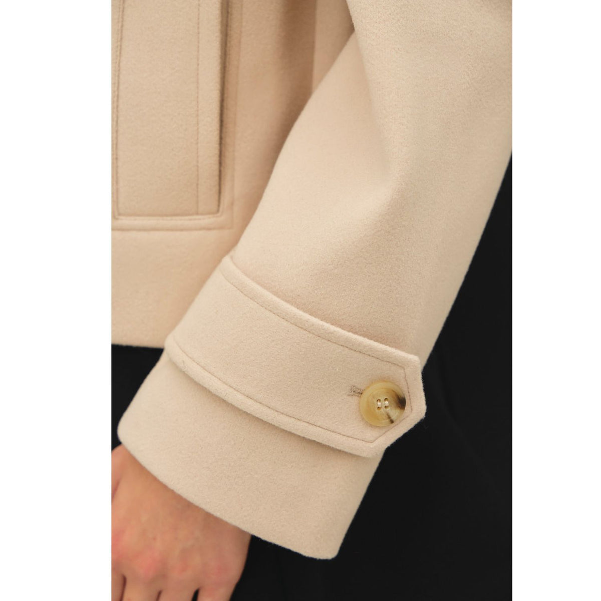 Women's neutral double-breasted cropped peacoat with wide notched lapels, button-tab cuffs, and a relaxed boxy fit