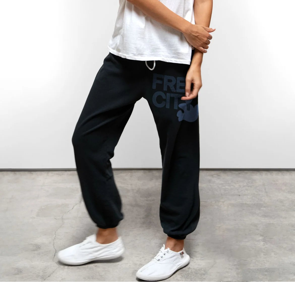 Relaxed-fit fleece pants with an elastic waistband and drawstring, featuring a graphic detail on the leg, styled with a tee and sneakers.