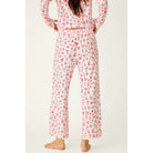 Ivory cropped pajama pants with red holiday print, smocked waistband, and open-leg silhouette